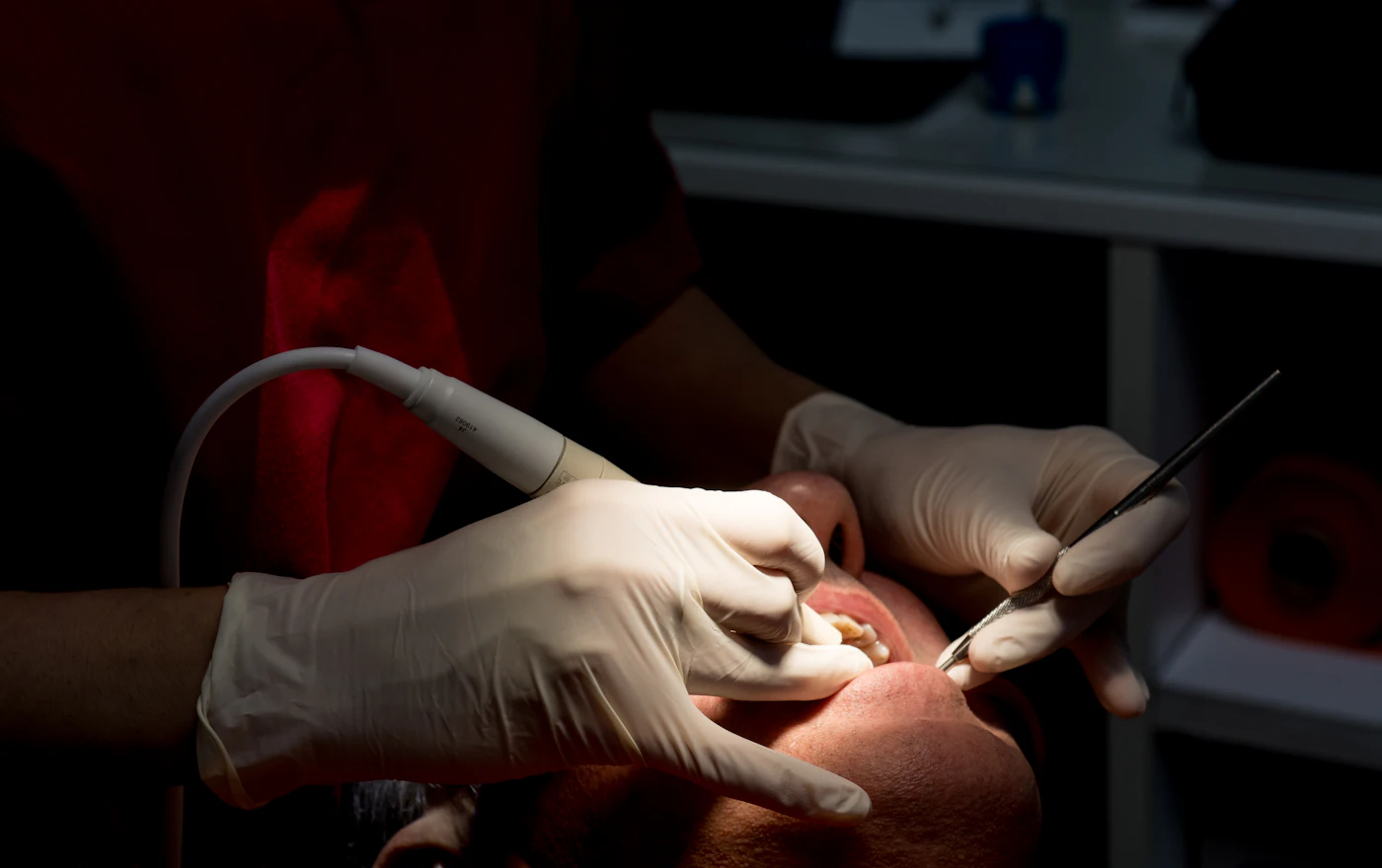 A dentist cleaning a patient's teeth with a scaling tool